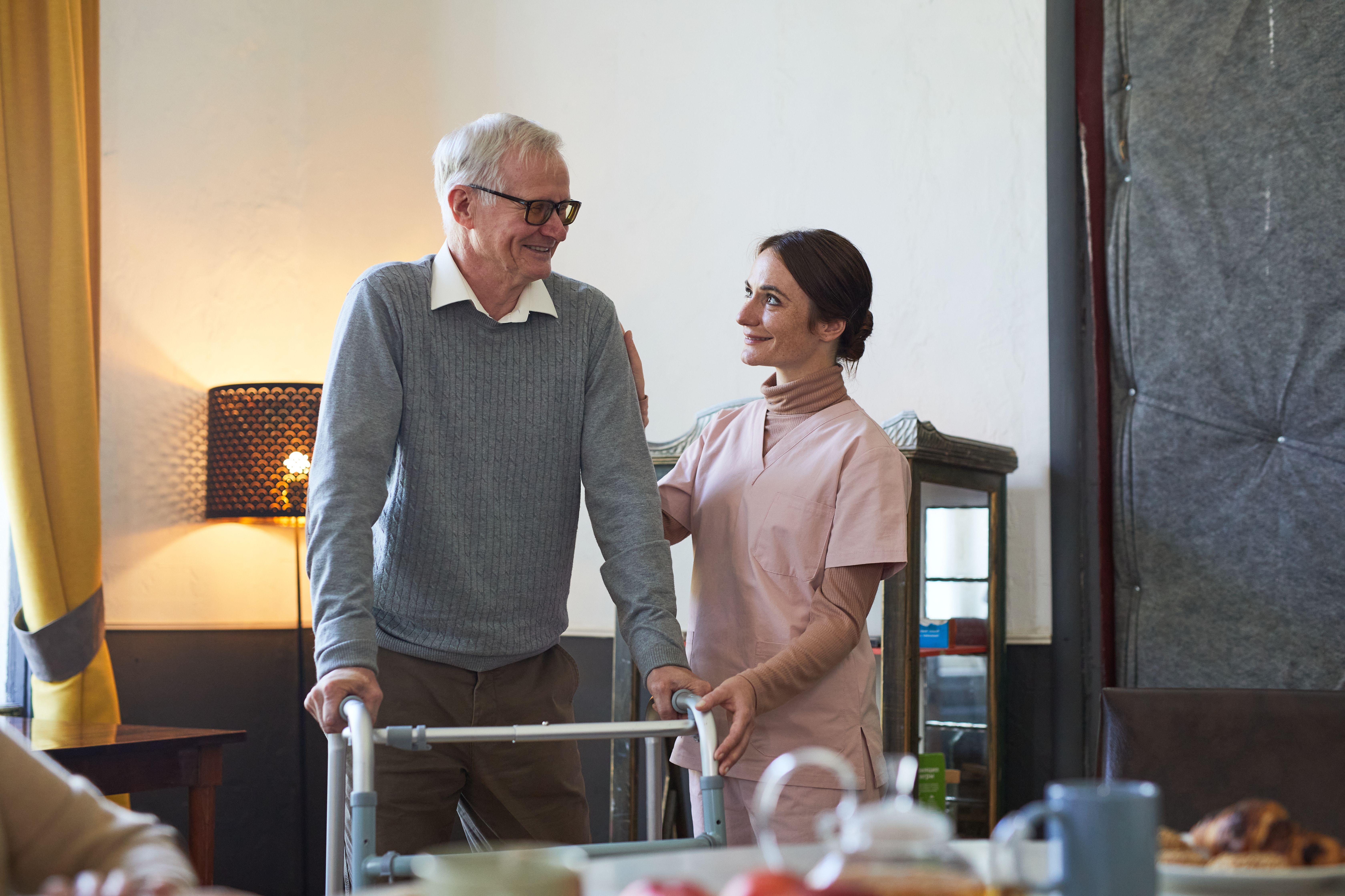 hc24q portrait smiling young woman helping senior man using walker nursing home copy space